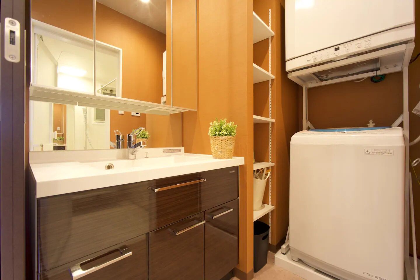 A modern bathroom with a white sink, dark wooden cabinets, a mirror, and a white water heater.