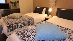 Une chambre d’hôtel avec deux lits, chacun agrémenté de draps à motifs et d’une lampe de chevet.