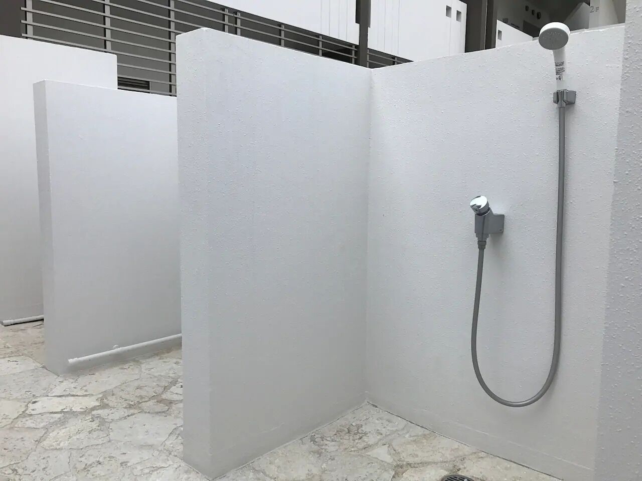 A modern bathroom with white partitions, a shower area, and a marble floor.