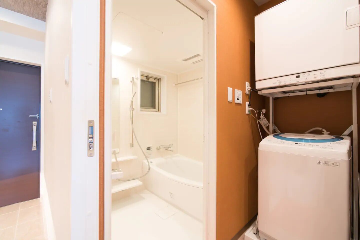 Une pièce avec une baignoire, des toilettes et un appareil blanc avec un dessus bleu, qui pourrait être un chauffe-eau ou un radiateur.