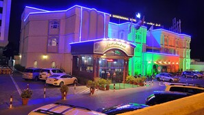 A hotel with a traditional architectural style, featuring a prominent entrance and multiple parking spaces. - Bowshar International Hotel (Muscat)