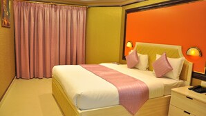 A hotel room with a large bed, a nightstand, and a wall-mounted lamp. - Bowshar International Hotel (Muscat)