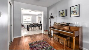Uma sala de estar com um piano, um tapete estampado e obras de arte na parede.