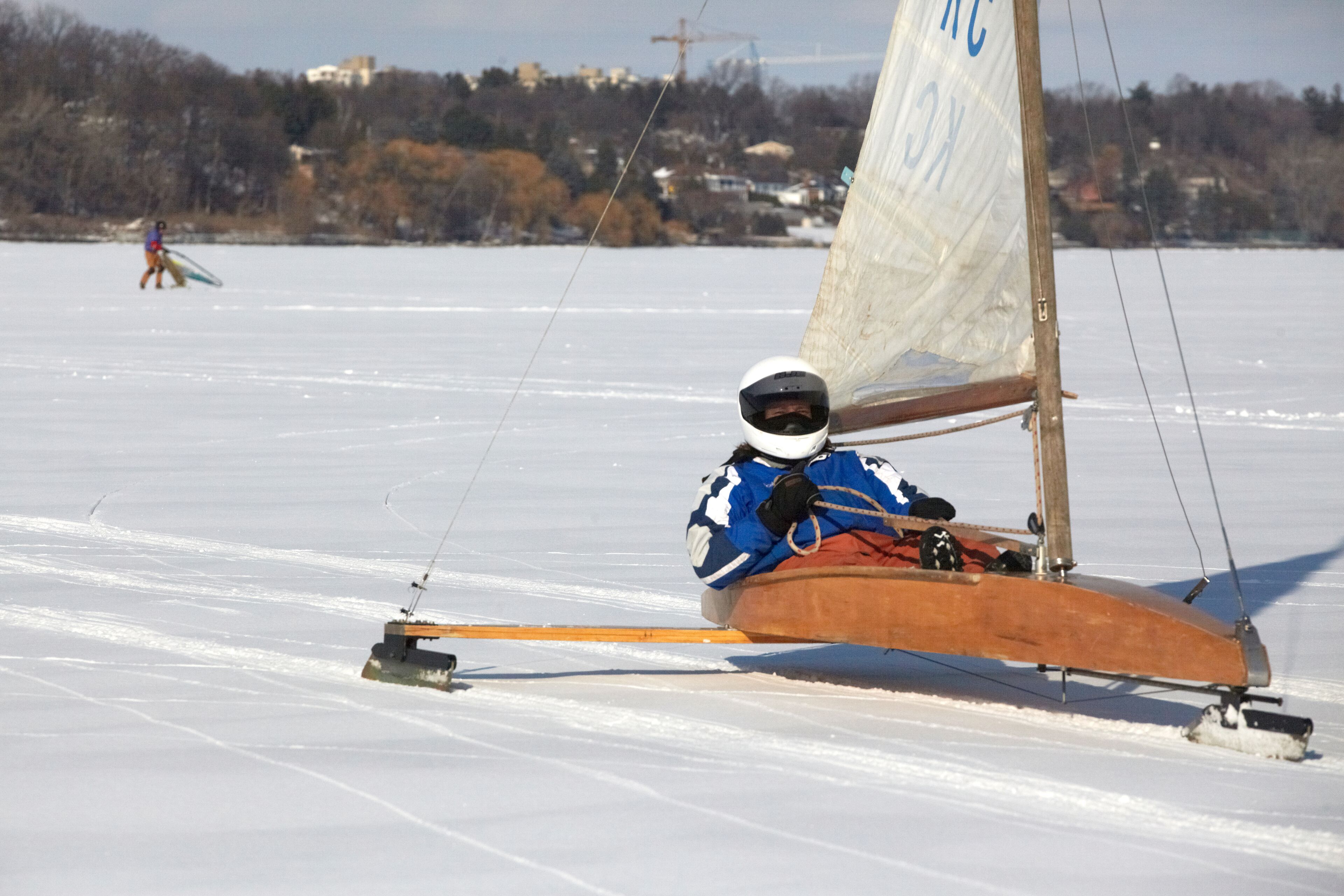 Eine Person in einem Segelboot auf einem zugefrorenen See.