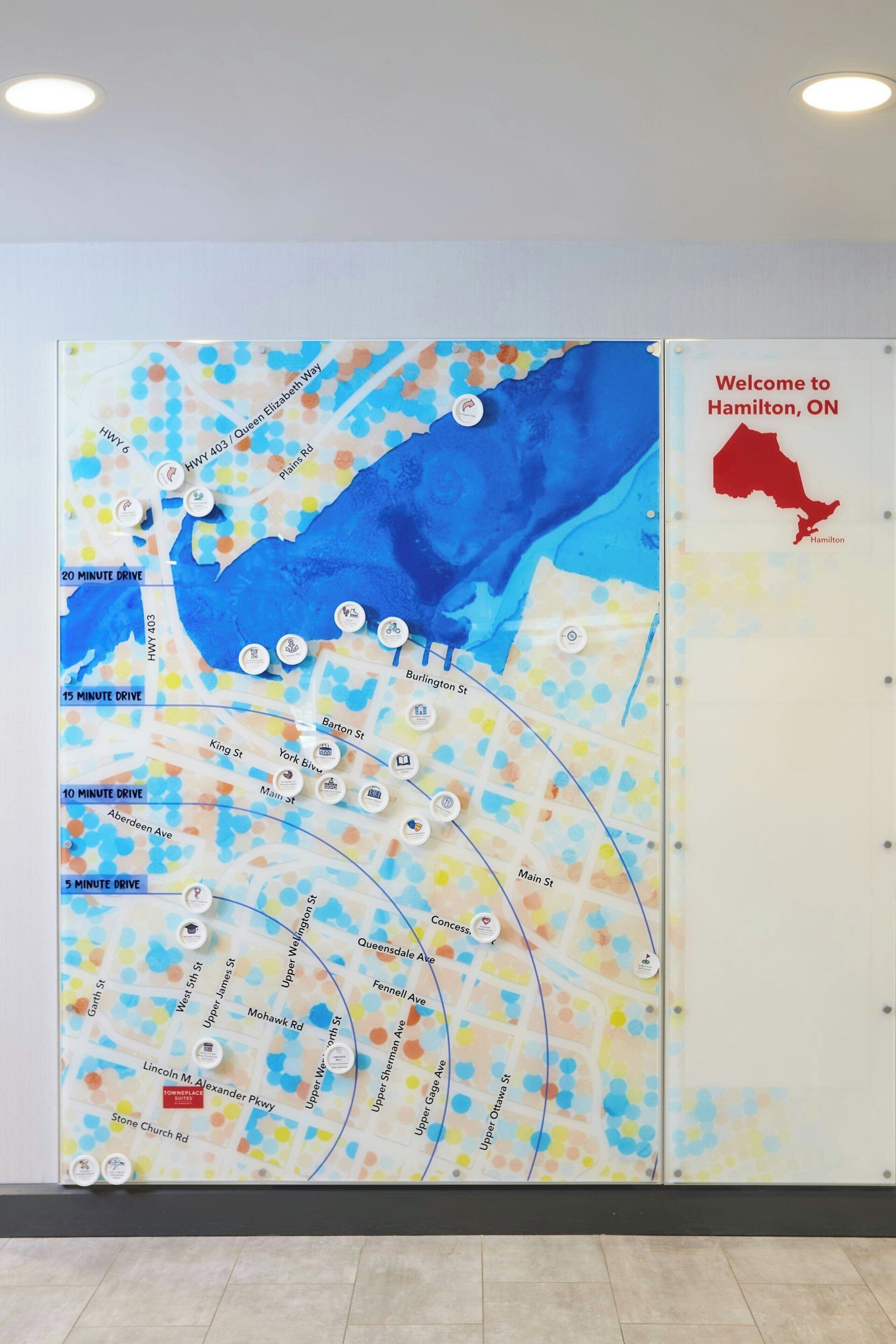 A map with various streets and drive times, a welcome sign for Hamilton, ON, and a red outline of the city.
