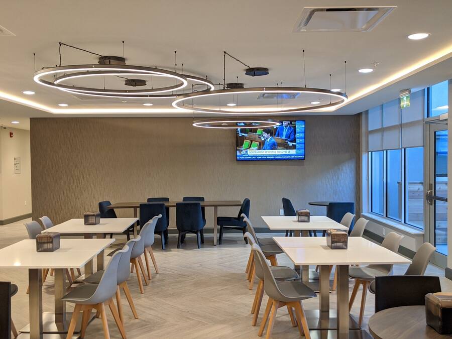 A modern conference room with a large flat-screen TV, multiple tables, and chairs.