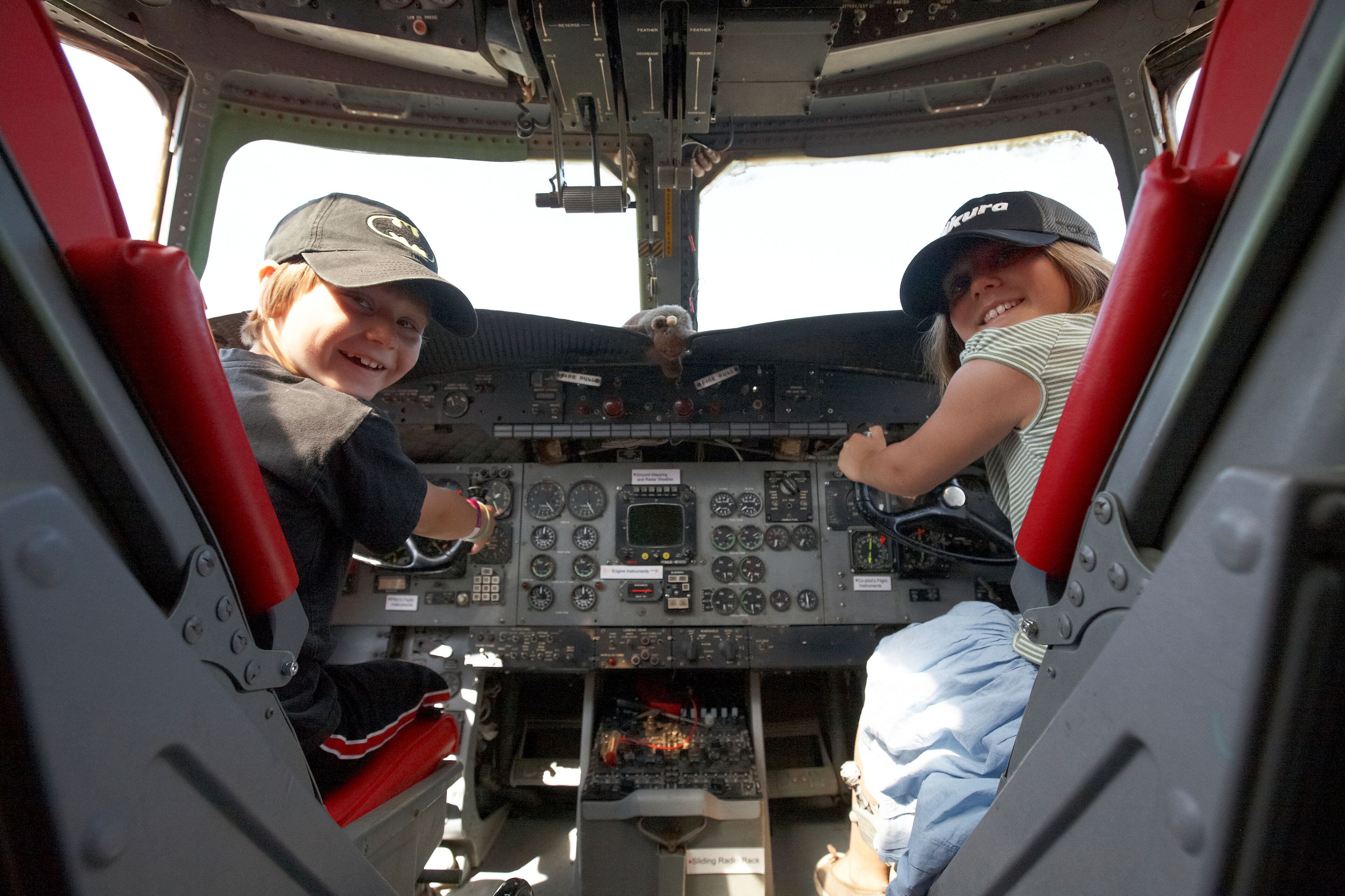 A cockpit with two individuals, one on each side, and a control panel with various dials and switches.