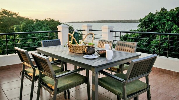 Een tafel buiten opgesteld met stoelen, een mand en uitzicht op het water.