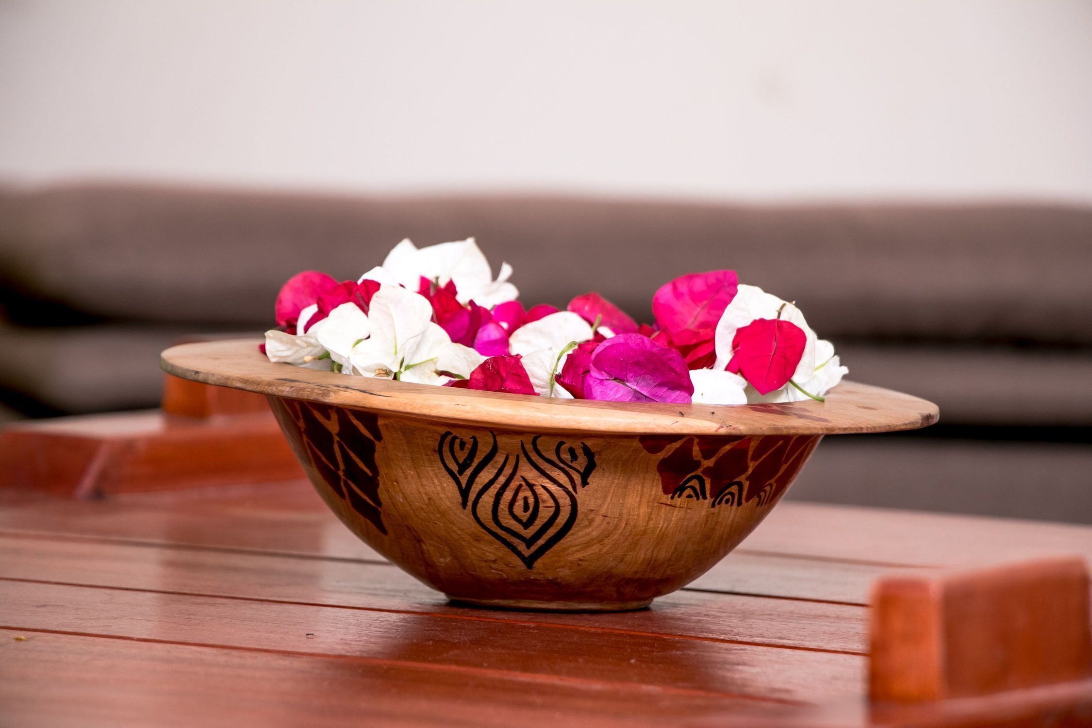 A wooden bowl with floral designs on a wooden table.