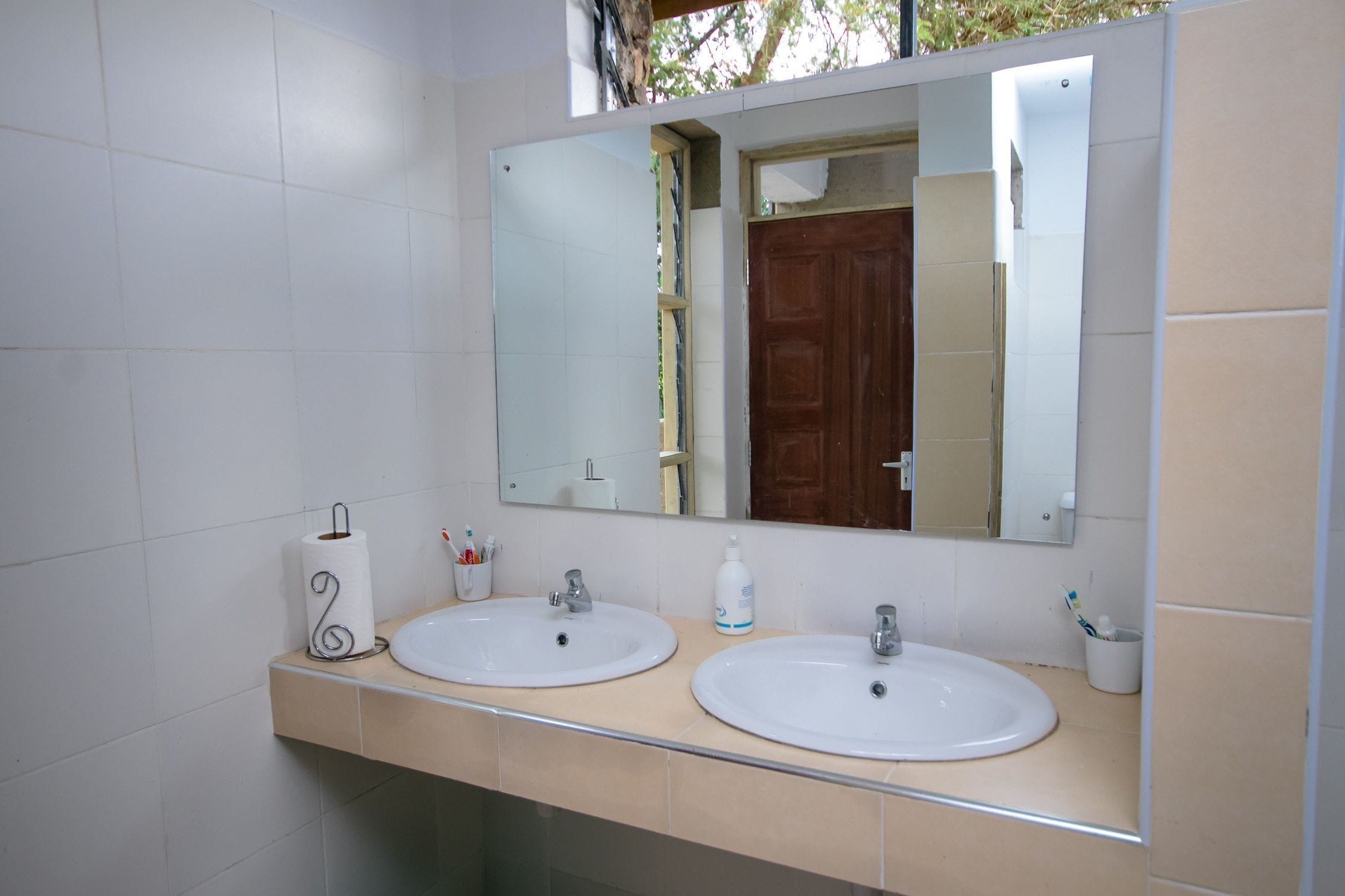 Un baño con dos lavamanos, un espejo y un dispensador de toallas.