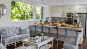 Een moderne keuken met witte kasten, een houten aanrecht en een eethoek met stoelen.