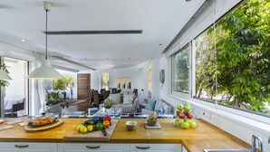 Een moderne keuken met een houten aanrecht, een spoelbak en een groot raam met beplanting erbuiten.