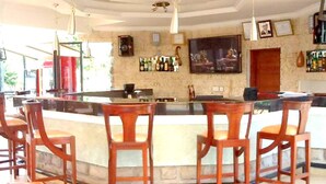 A bar area with wooden chairs and a counter. - Desert Rose Resort (Kisumu)