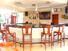 Uma área de bar com cadeiras de madeira e um balcão.