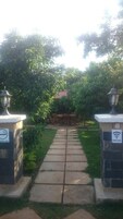 Um caminho leva a uma área de estar com mesa e cadeiras, ladeada por postes de luz e uma placa indicando área para fumantes.