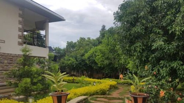 A pathway leading to a building with a stone facade and a balcony. - Desert Rose Resort (Kisumu)