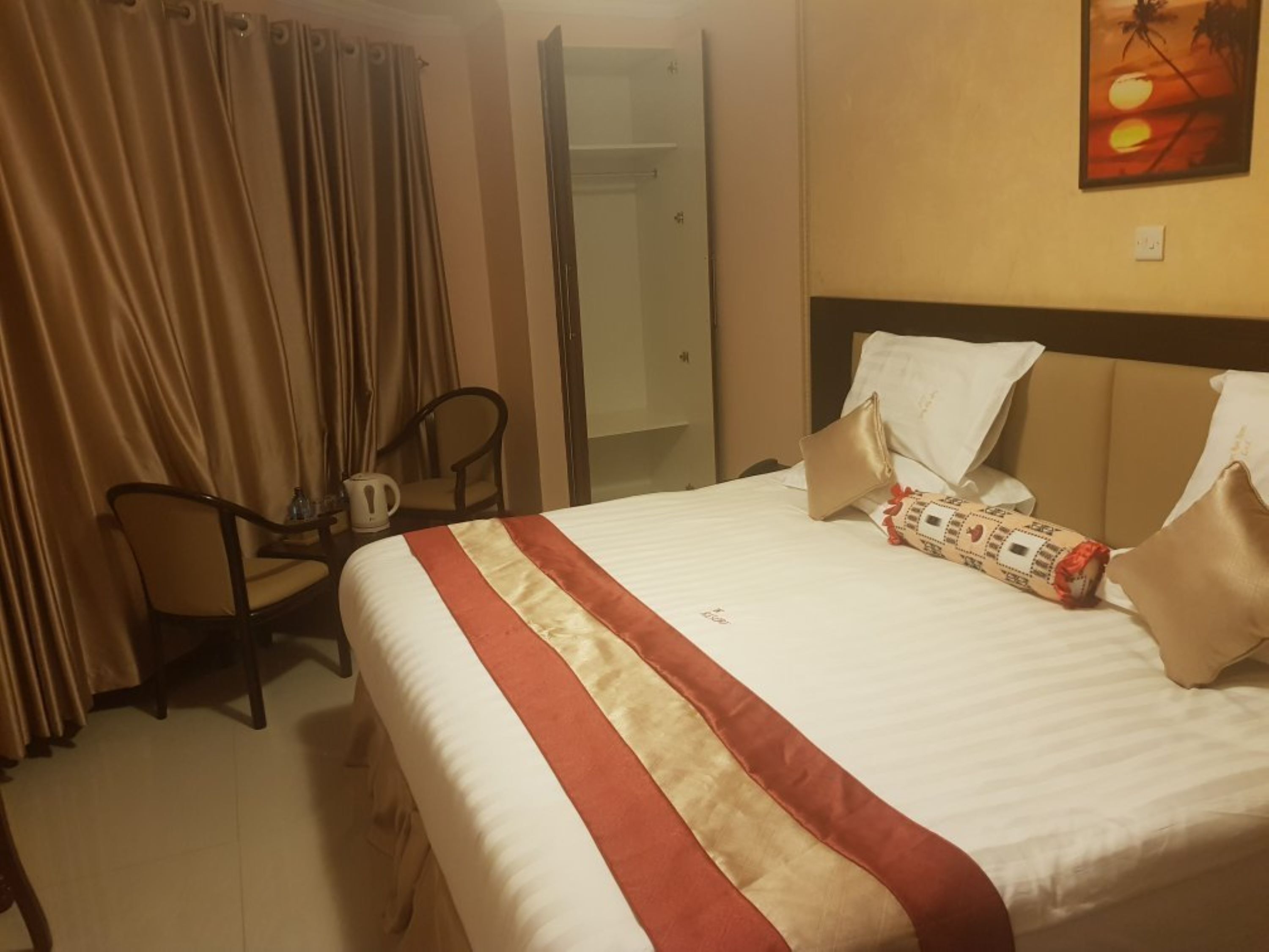 Ein Hotelzimmer mit einem Bett, einem Sessel, einer Kaffeemaschine und einem Bild an der Wand.