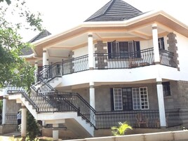 Uma casa de vários andares com varanda, escadaria e um pequeno jardim.
