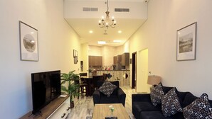 A modern living room with a flat-screen TV, a coffee table, and a sofa with patterned cushions. - Marbella Executive 2 Bedrooms (Dubai)