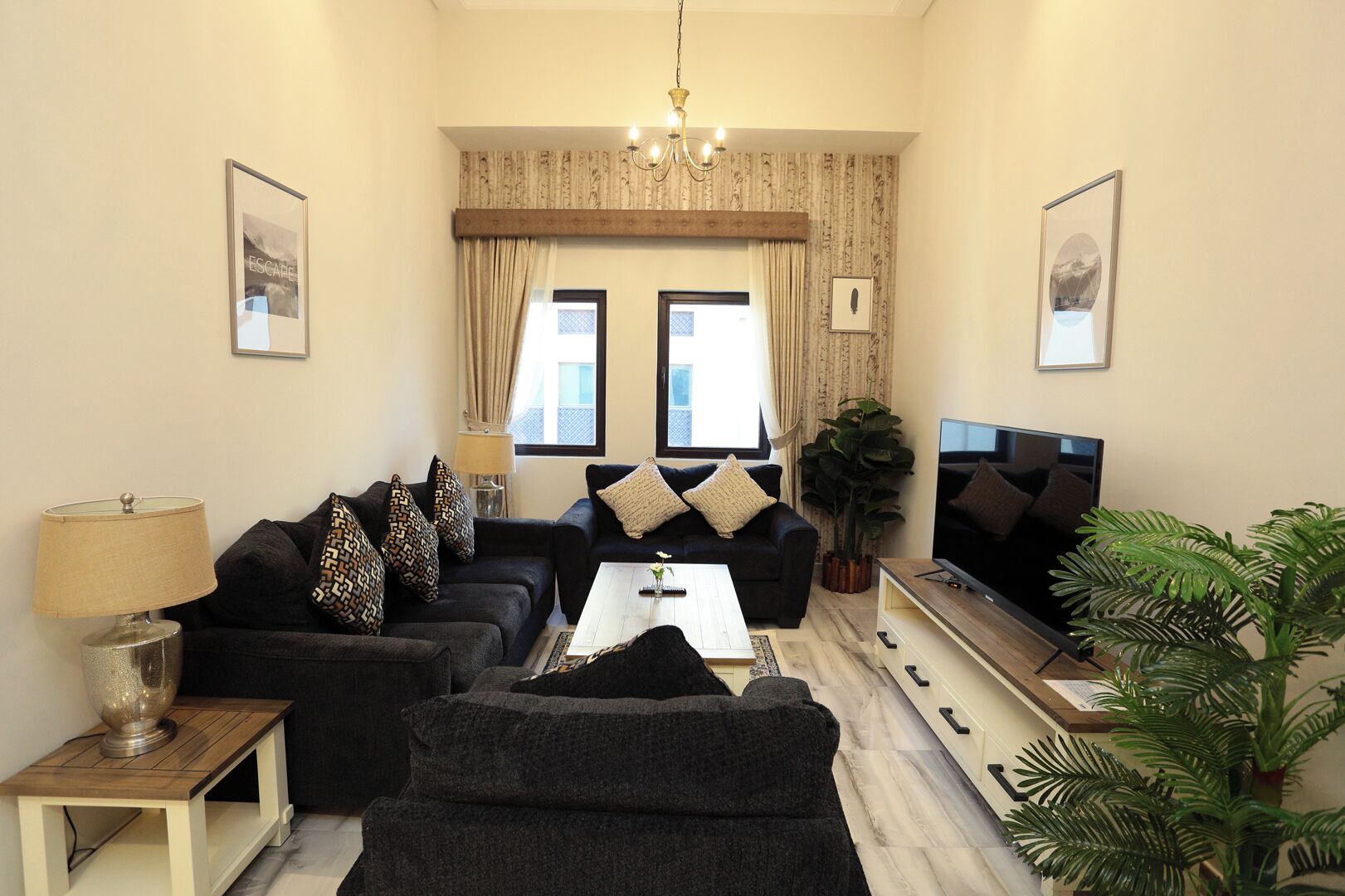 A modern living room with a sofa set, a coffee table, a TV, and a chandelier.