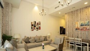 A modern living room with a sofa set, a coffee table, and a dining area with chairs and a table. - Marbella Executive 2 Bedrooms (Dubai)