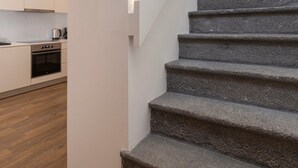 A staircase leading to a second floor with a modern kitchen visible on the landing. - Casa Amarela 22 (Azores Premium at city center) (Ponta Delgada)
