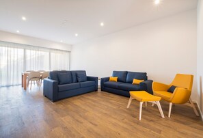 A modern living room with two sofas, a yellow armchair, and a dining area with a table and chairs. - Casa Amarela 22 (Azores Premium at city center) (Ponta Delgada)