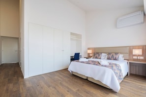 A hotel room with a large bed, a wardrobe, a desk, and an air conditioning unit. - Casa Amarela 22 (Azores Premium at city center) (Ponta Delgada)
