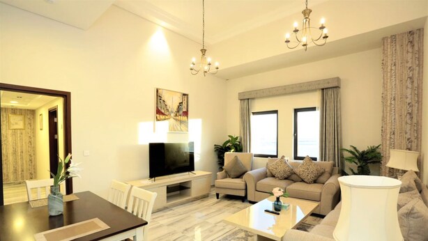 Una sala de estar moderna con un televisor de pantalla plana, un sofá, una mesa de centro y un comedor con una mesa y sillas.