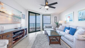 A living room with a sofa, coffee table, TV, and a balcony with a view.