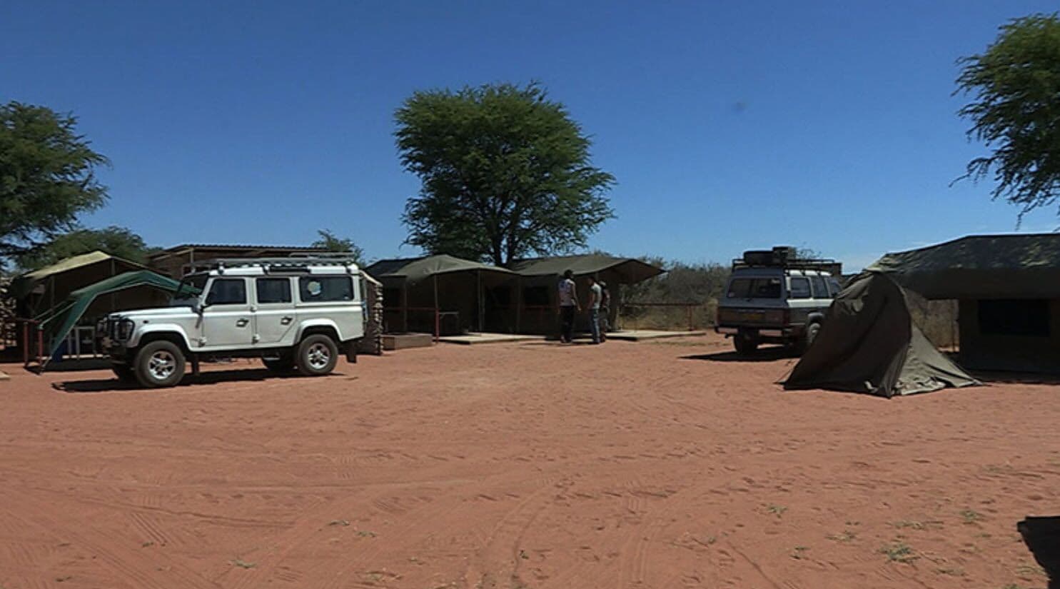A campsite with tents, a white SUV, and a truck.