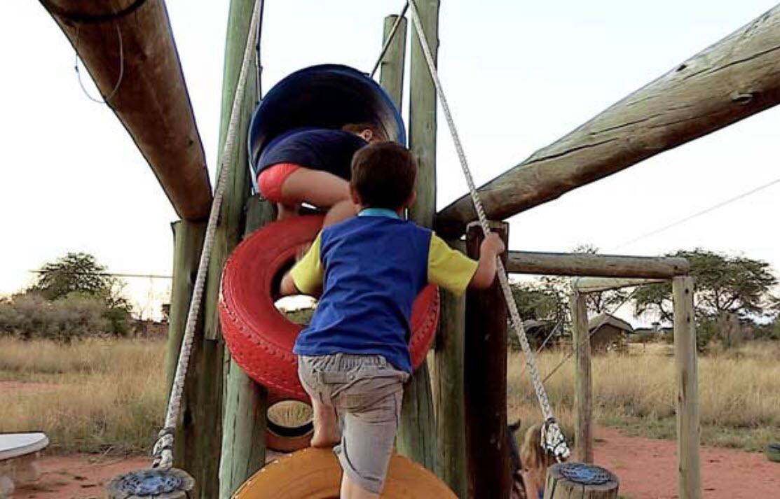 A wooden playground structure with a tire swing and a slide.