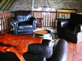 Decoração rústica com sofás de couro, um barril de madeira e uma parede de tijolos.