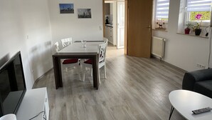Een moderne woonkamer met een eethoek, een televisie en een bank.