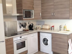 A compact kitchen with a microwave, oven, dishwasher, and a sink.