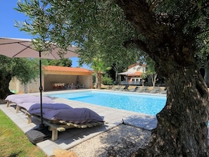 A swimming pool with lounge chairs and a pergola.