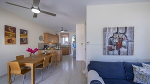 A modern kitchen with wooden cabinets, a dining table with chairs, and a ceiling fan. - Protaras Villa Marilia Near Fig Tree Bay Beach (Protaras)