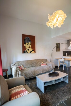 Een moderne woonkamer met een bank, een bijzettafeltje en een eethoek met een stoel en een tafel.