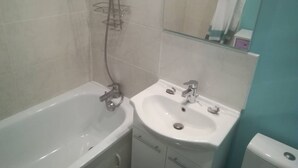 A bathroom with a bathtub, a sink, and a mirror. - LUMINOUS Apartment (strasbourg)