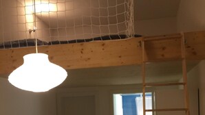 Una stanza con soffitto in legno, un lampadario a sospensione, una panca nera e una scala in legno.
