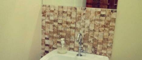 A bathroom with a white sink, a mirror above it, and a tiled backsplash.