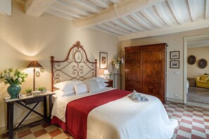 Un dormitorio con cama, armario de madera, mesita de noche, lámpara y un jarrón con flores.