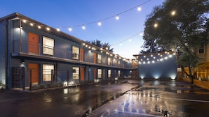 Un edificio de dos pisos con fachada azul, puertas naranjas y el suelo húmedo, probablemente después de la lluvia.