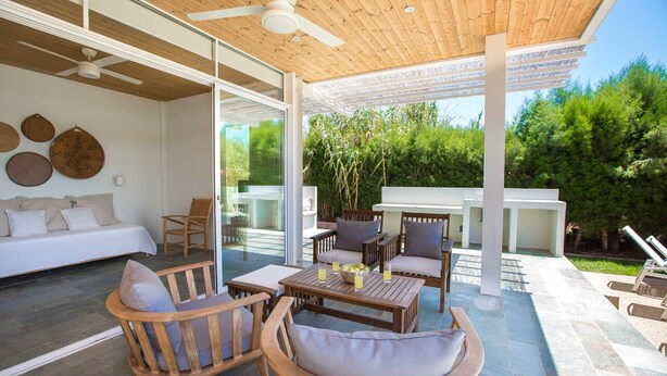 Un espace extérieur abrité, aménagé avec du mobilier en bois, un canapé et un ventilateur de plafond.