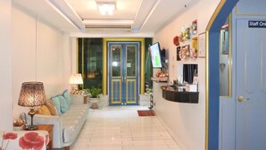 A reception area with a sofa, lamps, a TV, and a blue door labeled "Staff Only". - Pratunam Casa (Bangkok)