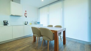 A modern kitchen with a wooden table and four chairs, a coffee maker, and a kettle on the counter.