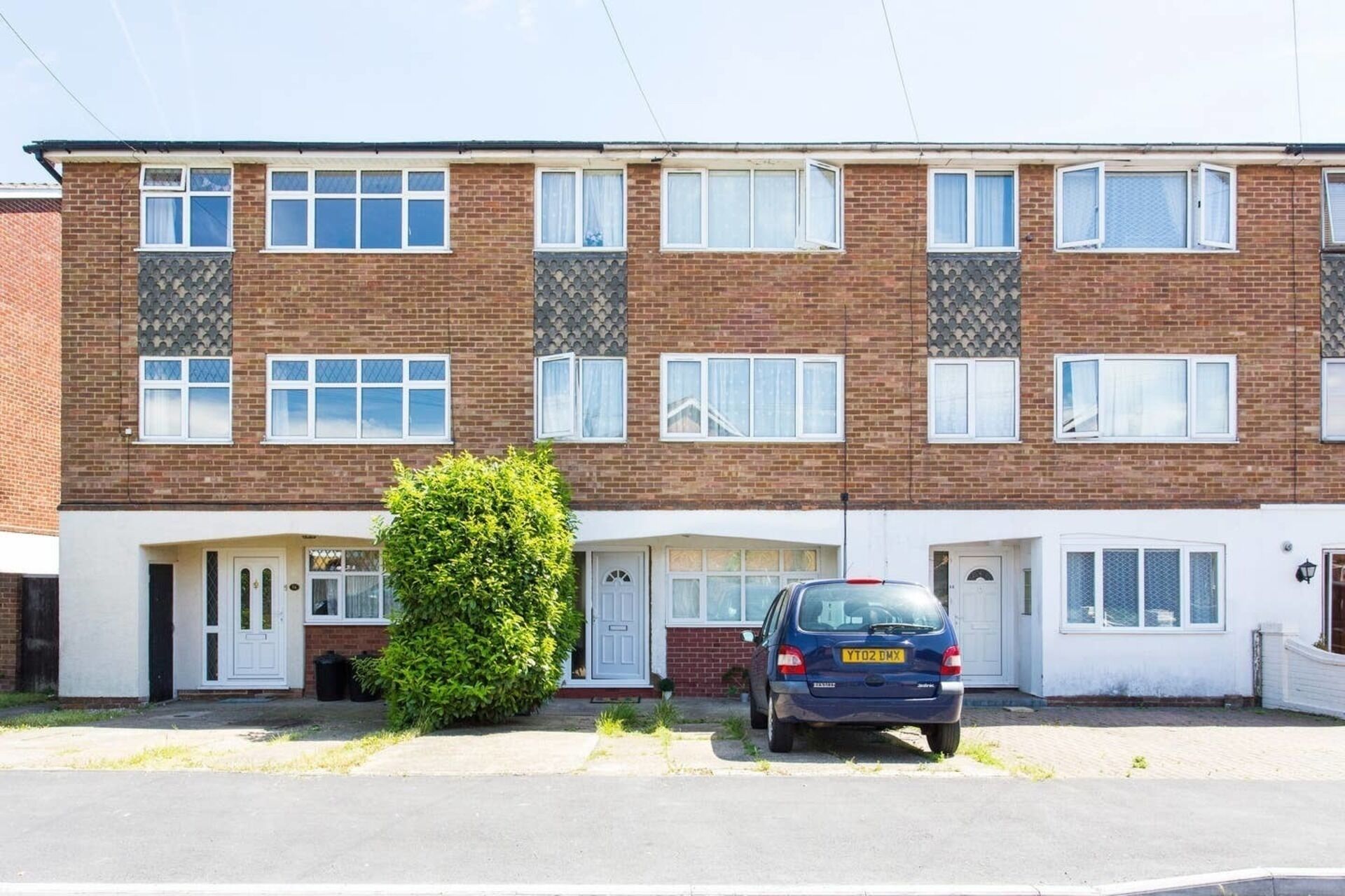 A two-story residential building with a car parked in front.