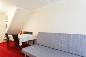 Una habitación con una mesa de comedor, cuatro sillas, un sofá gris y una decoración roja con forma de corazón.