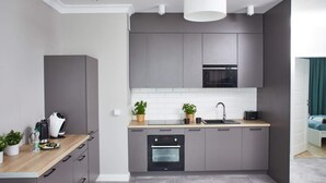 Een moderne keuken met grijze kastjes, een houten aanrechtblad, een ingebouwde oven en een spoelbak.