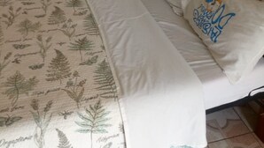 A bed with a floral-patterned bedspread, white pillows, and a wooden headboard.